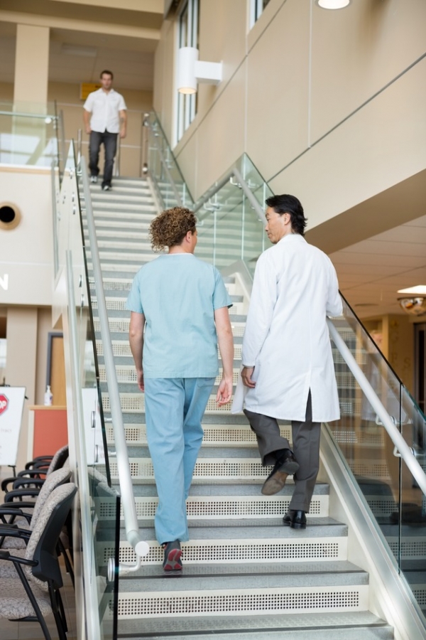 Doctor And Nurse Climbing Up Stairs In Hospital